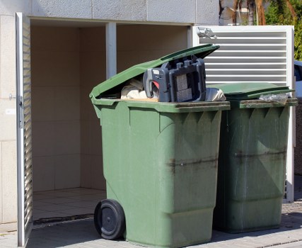 Workers wearing PPE loading a skip