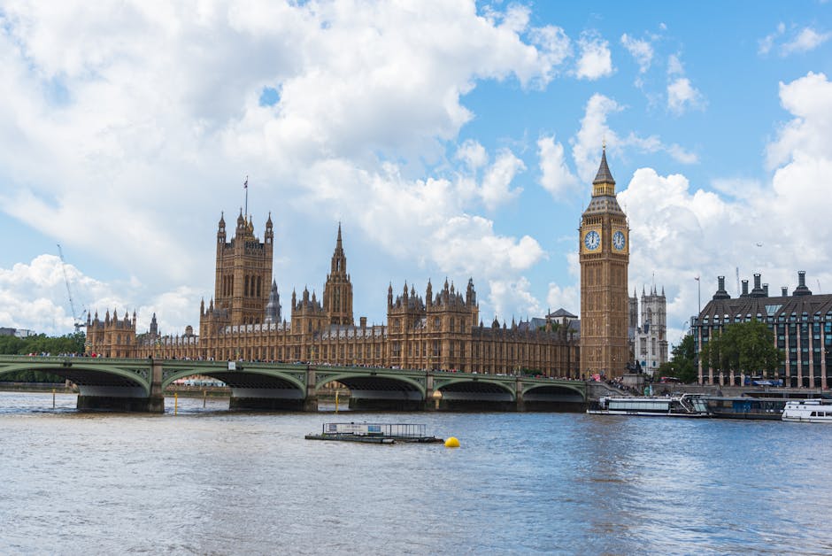 A wide-angle view of the Palace of Westminster in London, featuring the iconic Big Ben clock tower on the right side of the image. The historic Gothic-style building is constructed from stone with int